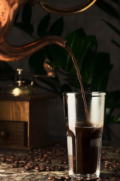 Brewing coffee coffee is poured into a glass cup from a copper coffee maker lunch in an old cafe Vertical shot selective focus