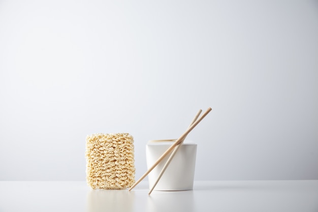 Brick of dry japanese noodles presented near closed blant retail takeaway box with chopsticks
