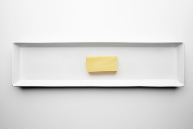 Brick of Mozzarella cheese isolated on white plate, top view. Any other solid cheese without holes.