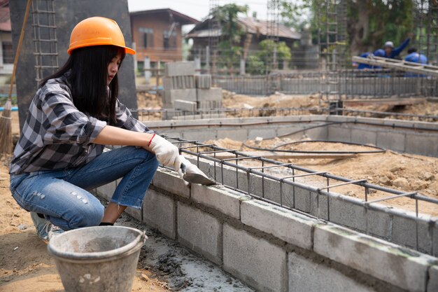 Bricklayer worker installing brick masonry on exterior wall with trowel putty knife