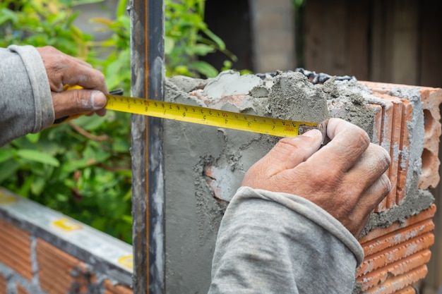 Foto gratuita muratura. muratore che costruisce un muro di mattoni.