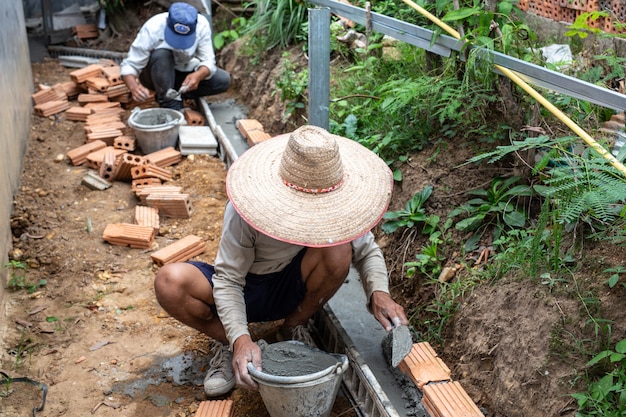 免费照片砌砖。建筑工人建造一堵砖墙。