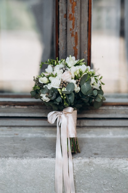 Foto gratuita il bellissimo bouquet da sposa con un tipo di raso si trova sulla finestra