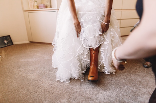 花嫁は彼女の足に赤いブーツを調整する