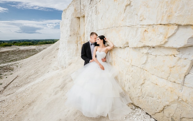Бесплатное фото Жених и невеста в день свадьбы, прогулки на открытом воздухе возле горы вулканического песка.