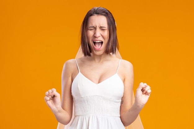 Bride in beautiful wedding dress happy and excited clenching fists shouting