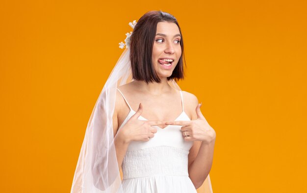Невеста в красивом свадебном платье смотрит в сторону счастливым и радостным, высунув язык