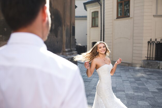 Bride dancing in the street while her husband watches