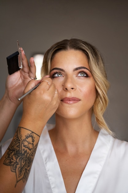 Free photo bride getting makeup ready for wedding front view