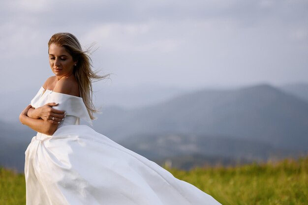 산 보기와 초원에 서 있는 흰 드레스에 신부 소녀