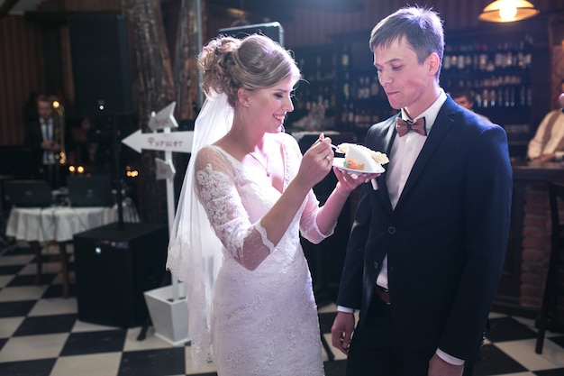 Free photo bride giving boyfriend a piece of cake