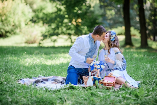 Bride and groom dressed in blue Ukrainian national clothes kiss on the blanket 