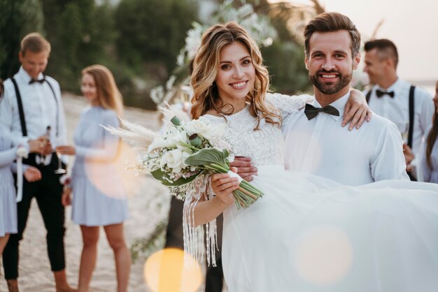 ビーチでゲストと結婚式をしている新郎と新婦
