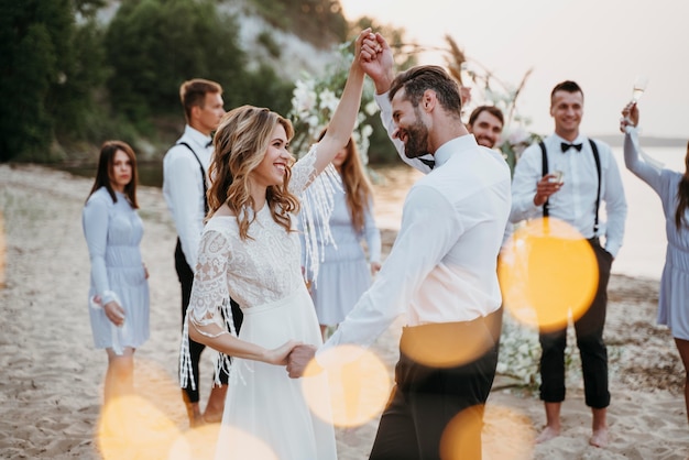 Gli sposi festeggiano il loro matrimonio con gli ospiti sulla spiaggia