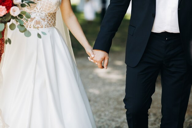 Bride and groom hold each other hands standing before the arch