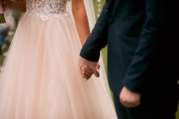 Жених и невеста держат друг друга за руки, стоя в церкви