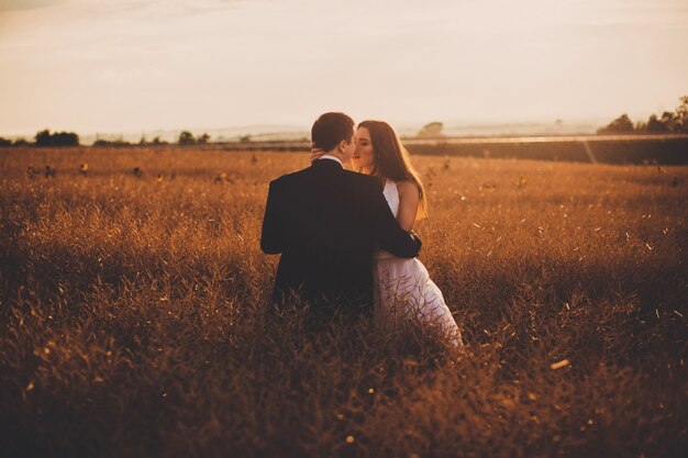 "Bride and groom hugging in field"