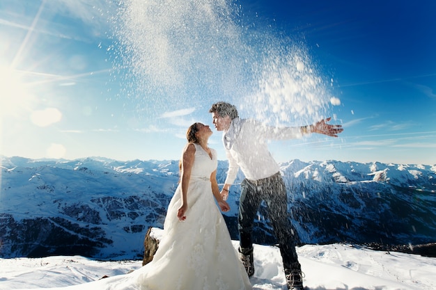 Жених и невеста в любви бросают снег на фоне Альп Куршевель