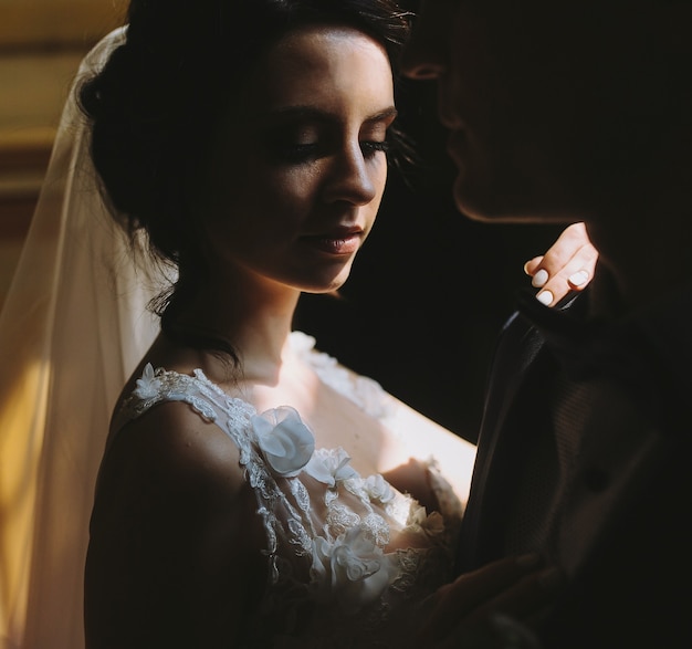 Жених и невеста позируют в тускло освещенной комнате