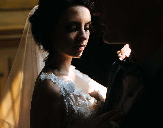 Жених и невеста позируют в тускло освещенной комнате