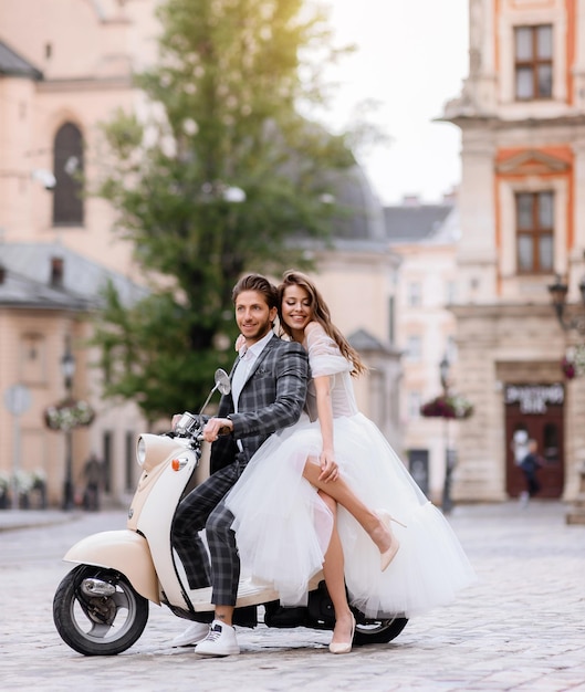 Bride and groom posing on vintage motor scooter