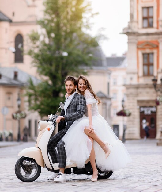 Bride and groom posing on vintage motor scooter