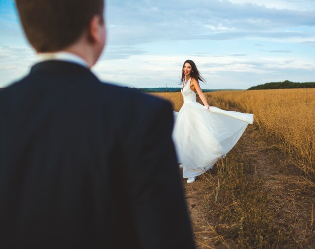 "Bride and groom standing in field"