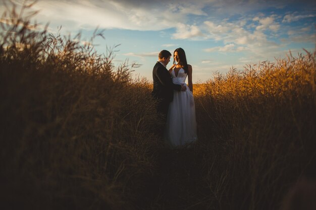 "Bride and groom standing in field"