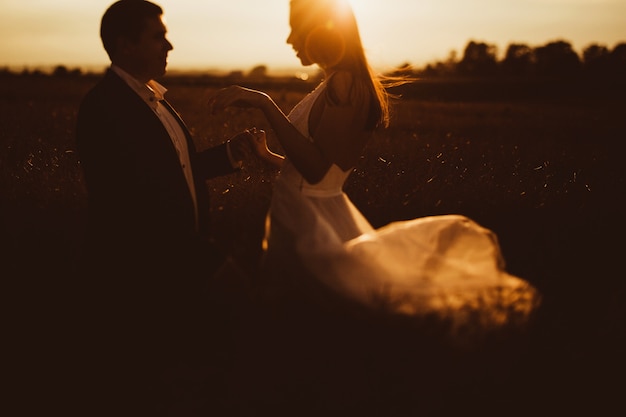 "Bride and groom standing in field"