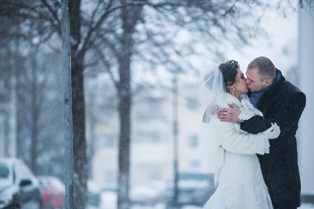 Bride and groom walking on the European city in the snow