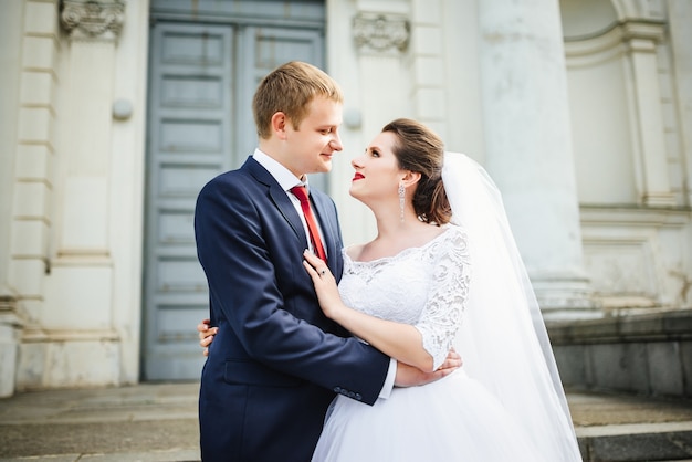 Bride and groom at wedding Day walking Outdoors near architecture. 