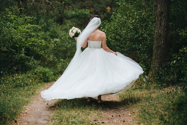 bride and groom with a bouquet of red flowers and greens in hand