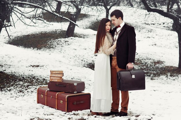 Bride and groom with old-fashioned suitcase stand in winter park