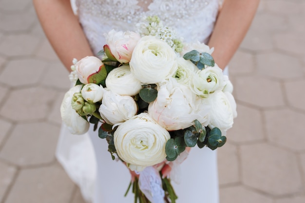 bride holding bouquet of white and pink ranunculus