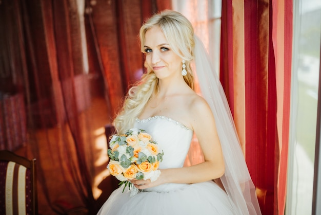 Bride holding a bridal bouquet with small yellow and pink roses 