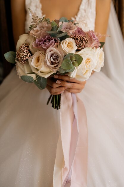 Bride holds beautiful bouquet with roses and eucalyptus