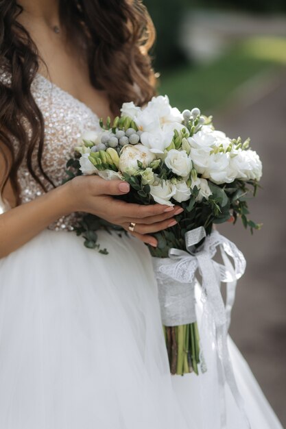 花嫁は白いバラと牡丹の美しいブライダルブーケを保持しています。