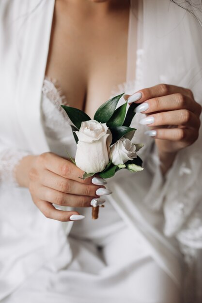 Bride holds a butonholle with roses