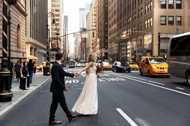 Bride holds groom's hand walking across the street in New York