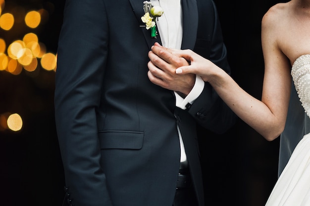 Free photo bride holds groom's hand while they stand outisde