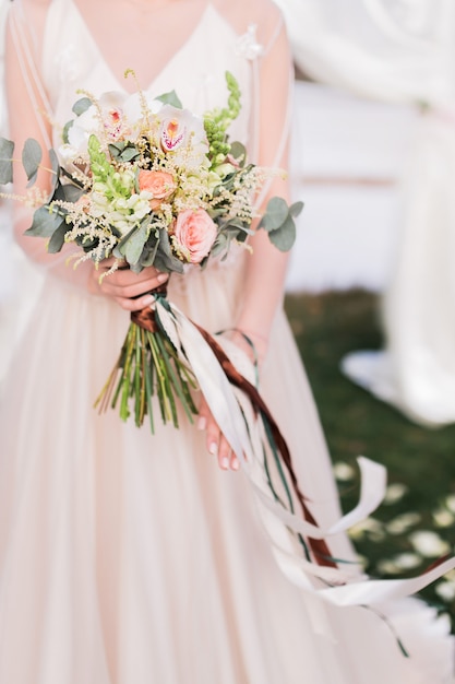 Bride holds in her hands rich bouquet with long stripes