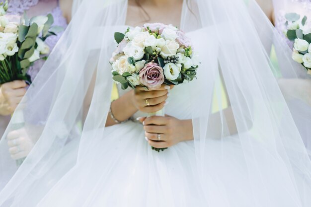 The bride holds a wedding bouquet in her hands