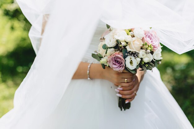 花嫁は結婚式のブーケを手に持っています