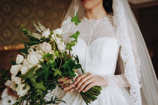 Bride holds wedding bouquet of white flowers in her hand