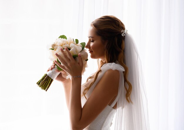 結婚式のブーケを保持し、嗅ぐ花嫁の結婚式のドレス