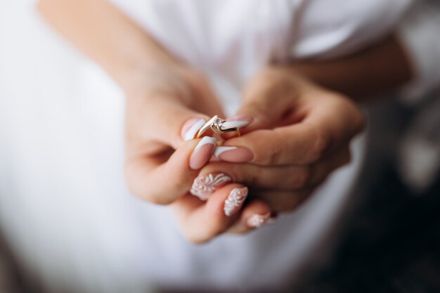 신부는 그녀의 손에 부드러운 약혼 반지를 들고있다