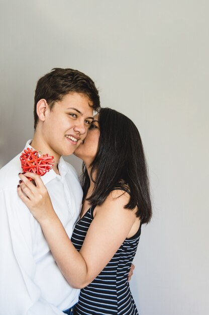 Bride kissing her boyfriend on the cheek with a heart in a hand