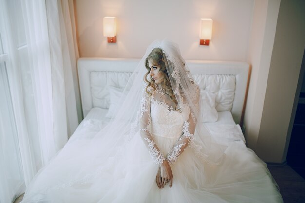 Bride kneeling on the bed with his hands clasped