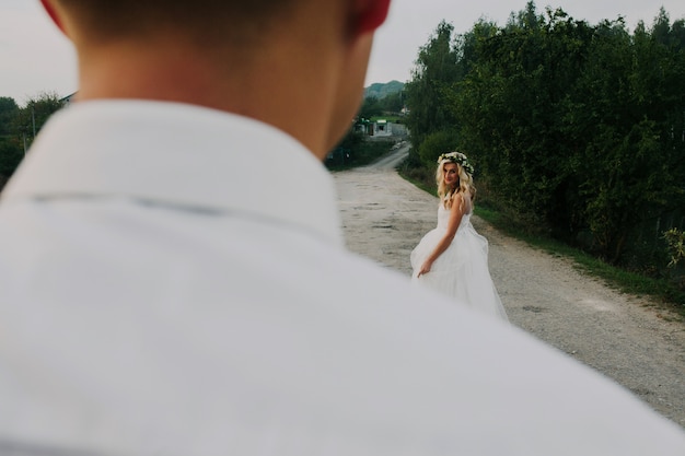 Foto gratuita la sposa conduce lo sposo sulla strada