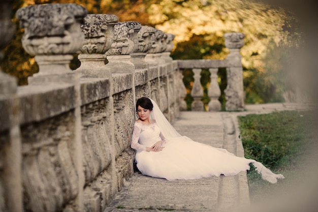 Bride leaning against a concrete fance